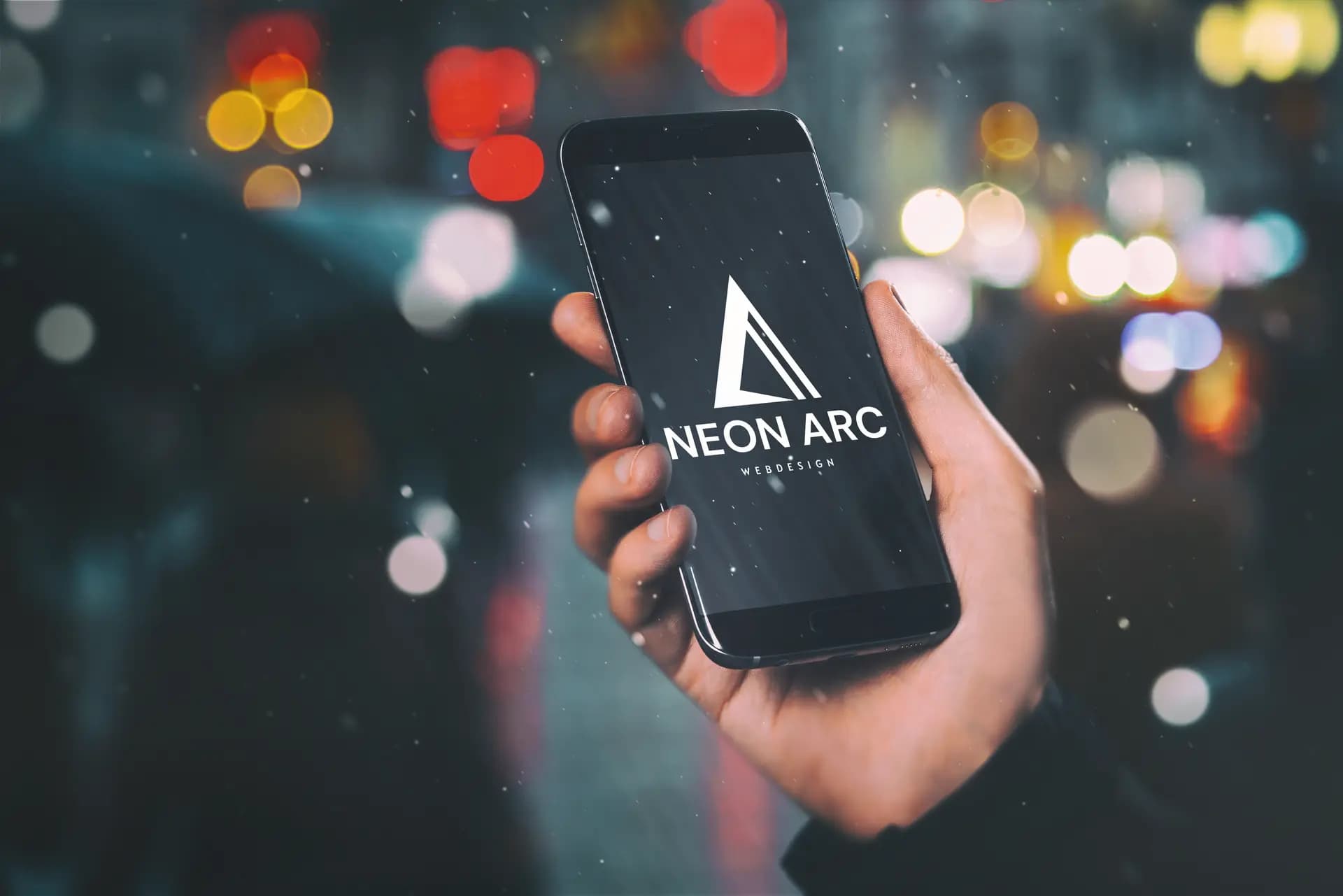 Hand hält ein Smartphone mit dem Neon-Arc-Logo bei Nacht — Sinnbild für Mobile-First-Design und Responsive Layouts auf jedem Gerät