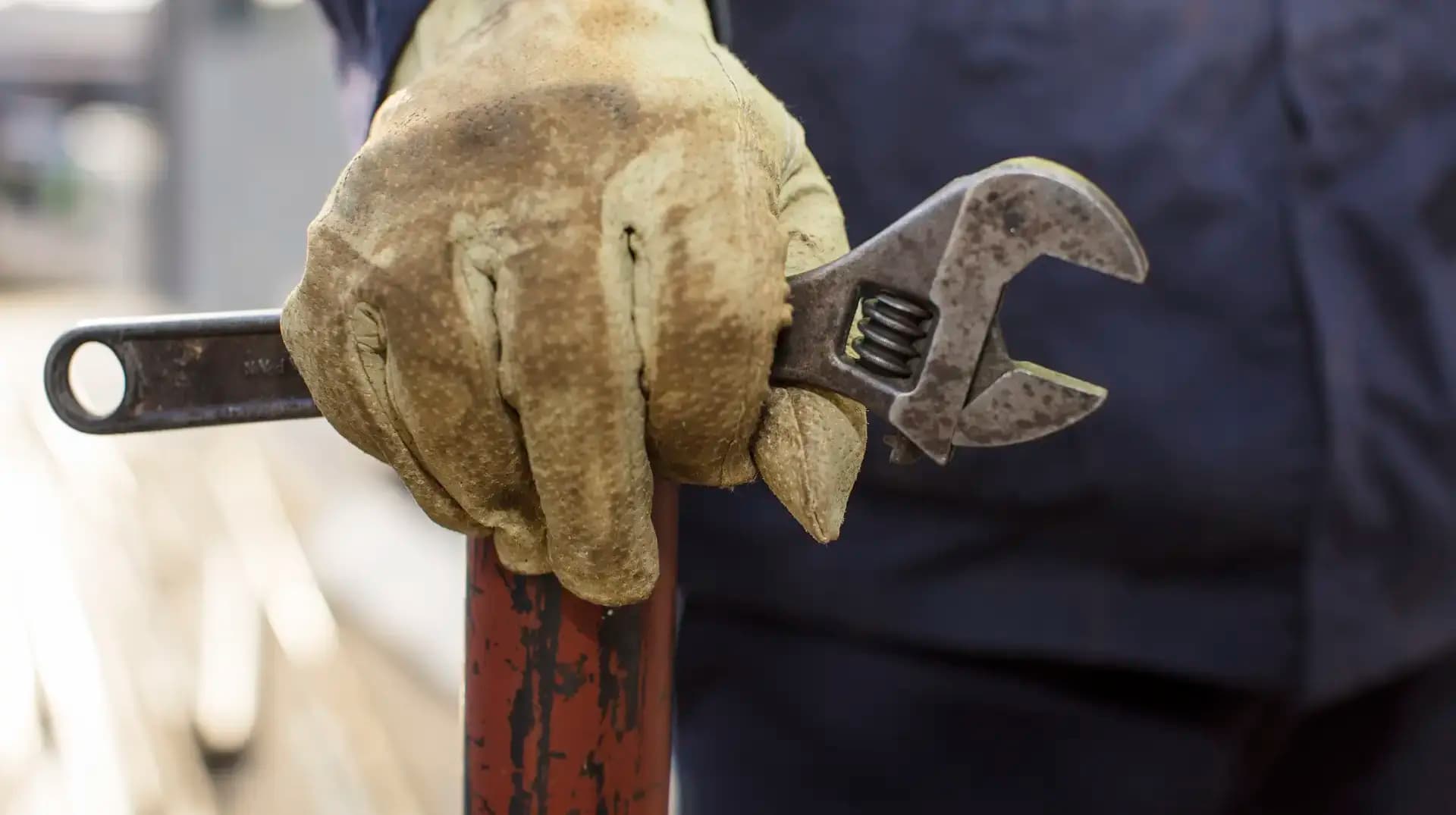 Hand mit Arbeitshandschuh und Schraubschlüssel an einem Rohr — Sinnbild für die handwerkliche Sorgfalt, die ein erfolgreicher Website-Relaunch verlangt