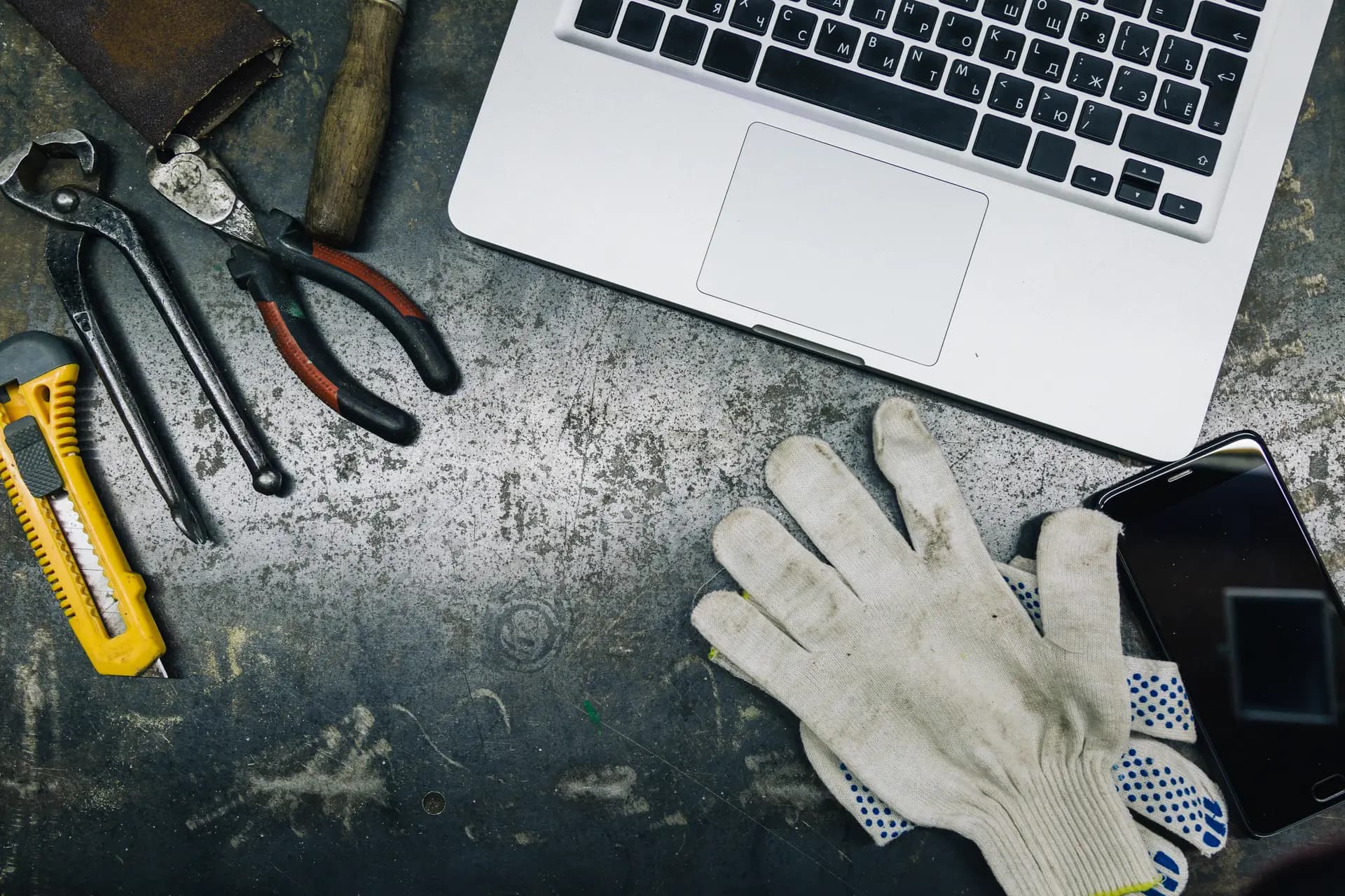 Werkzeug, Arbeitshandschuhe und ein Laptop auf einer Werkbank — Sinnbild für handwerklich gebaute Websites jenseits von Wix- oder Jimdo-Baukästen